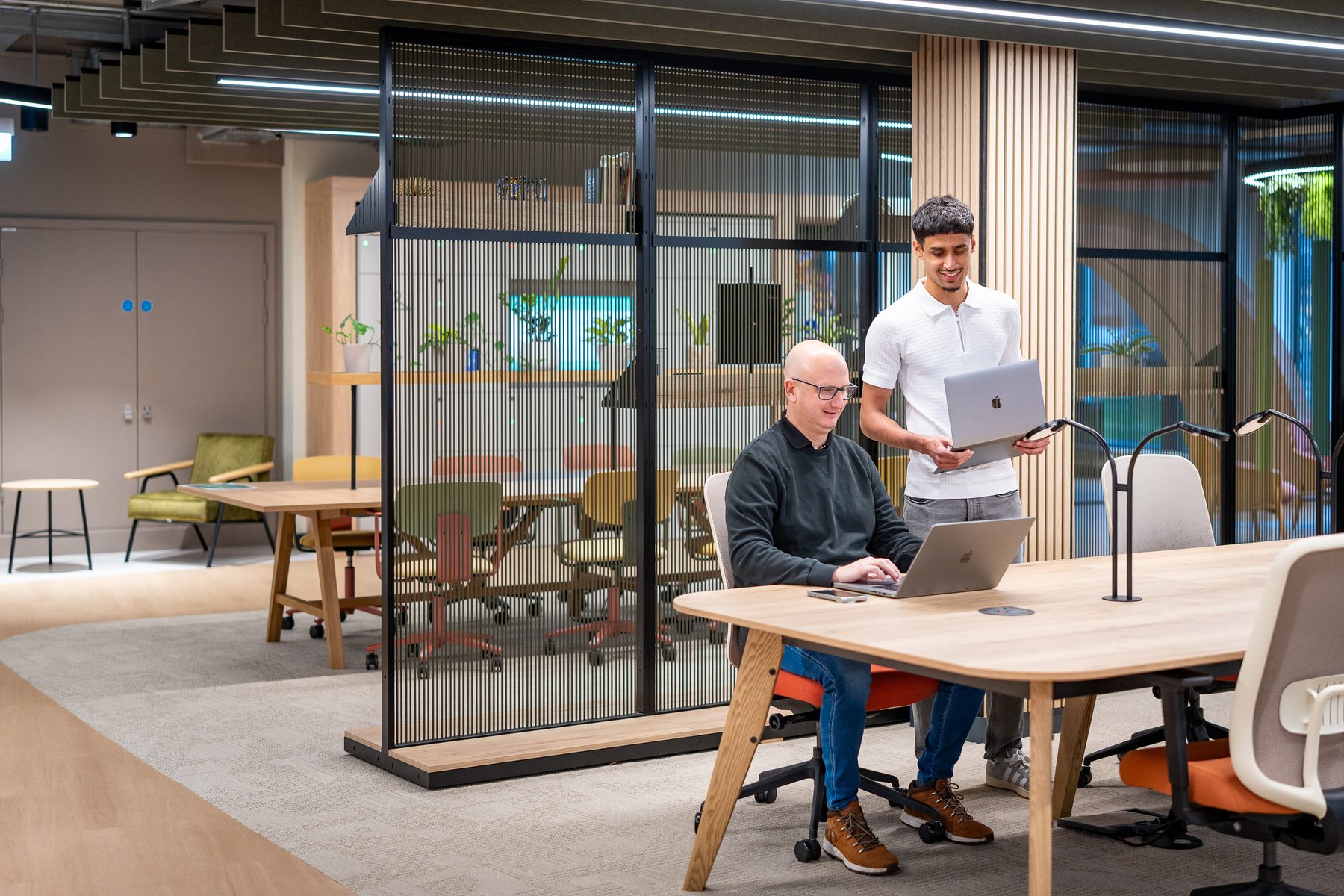 Two colleagues collaborating over a laptop in a modern office